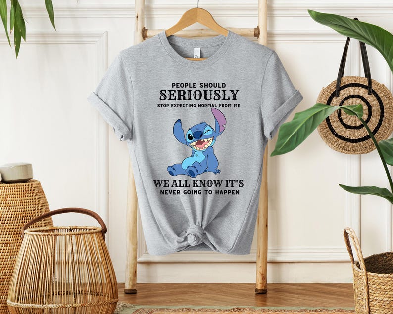 May include: Gray t-shirt with a blue Stitch character from Lilo & Stitch. The text on the shirt reads "People should seriously stop expecting normal from me. We all know it's never going to happen."