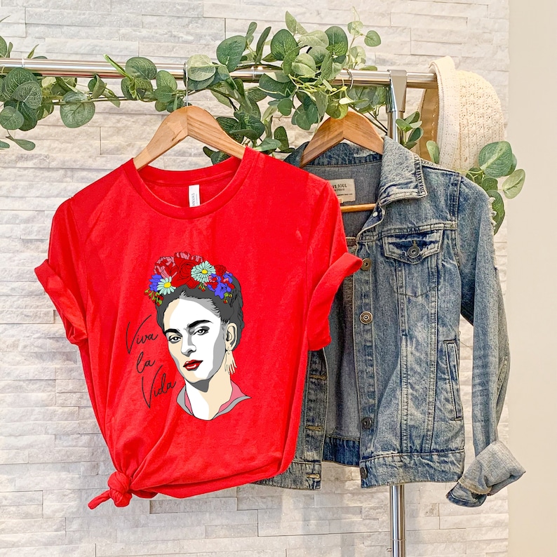 May include: Red t-shirt with a graphic of Frida Kahlo wearing a flower crown and the text "Viva la Vida".