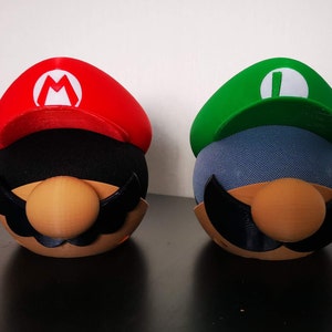 Mario and Luigi covers for Amazon Echo Dot. Mario is on the left using a black Echo Dot and Luigi is on the right using a white Echo Dot.