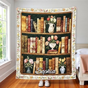 Pode incluir: Uma colcha decorativa com um design de estante com livros, vasos de flores e o nome "Sophia". A colcha tem uma borda floral e é exibida em uma cama.
