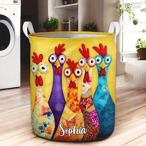 May include: A yellow laundry hamper featuring a whimsical design of five cartoon chickens with vibrant colors and patterns. The chickens have large eyes and red combs. The name "Sophia" is written in cursive on the front.