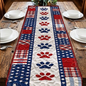 May include: A table runner with a central white panel adorned with red and blue paw prints. The edges feature red and blue plaid and star patterns. The runner is displayed on a wooden table.