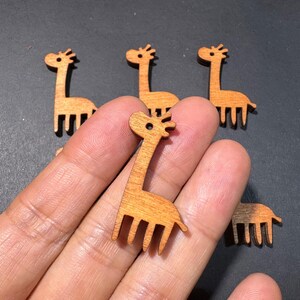 May include: Wooden giraffe cutouts in various sizes. The giraffes are light brown with a detailed design, including a long neck, small ears, and a tail. The giraffe cutouts are ideal for crafting and DIY projects.