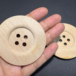 Puede incluir: Dos botones grandes de madera sin terminar con cuatro agujeros cada uno. Los botones son de color marrón claro y tienen un centro elevado. Los botones son redondos y parecen hechos a mano. Los botones son adecuados para manualidades y proyectos de costura.