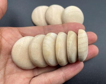 May include: A collection of unfinished, natural wood discs, some whole and some halved, are displayed. The discs are light beige in color and have a smooth, sanded appearance. They are likely intended for crafting or DIY projects.
