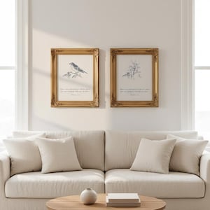 Op de afbeelding: Twee ingelijste prenten met gouden sierlijke lijsten hangen boven een beige bank. De prenten tonen botanische illustraties en tekst. Een ronde houten salontafel met een kleine vaas en boeken staat voor de bank.