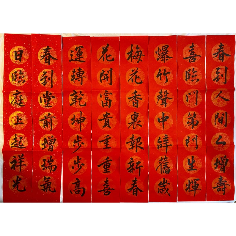 May include: Ten red paper scrolls with black Chinese calligraphy. The scrolls are decorated with gold flecks and each scroll has a different character written on it. The characters are: 宜, 春, 運, 花, 梅, 爆, 喜, 春, 臨, 到, 轉, 開, 花, 竹, 跨, 到, 庭, 堂, 乾, 富, 香, 声, 门, 人, 起, 增, 步, 重, 報, 辞, 斗, 祥, 瑞, 步, 新, 重, 禧, 生, 增, 光, 氣, 高, 喜, 春, 歲, 輝, 壽.