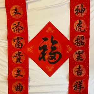 May include: Red and gold Chinese calligraphy scrolls with black ink. The scrolls feature traditional Chinese characters, including "福" (f&uacute;) meaning "good fortune" and "春" (chūn) meaning "spring".