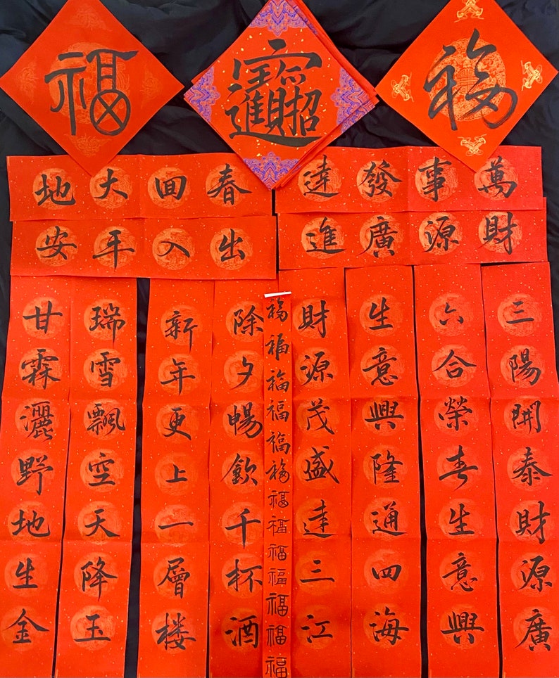 May include: Red and gold Chinese New Year calligraphy scrolls with black ink. The scrolls feature traditional Chinese characters and phrases, such as "prosperity", "wealth", and "good fortune".