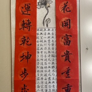 May include: Red and white Chinese calligraphy scrolls with black ink. The scrolls feature the characters "新更家萬" and "花岡富貴重重喜" and a black ink drawing of a lotus flower.