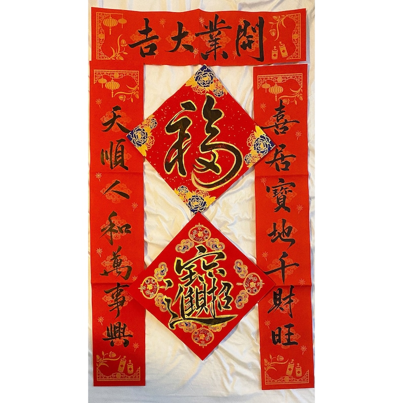May include: Red and gold Chinese New Year decorations with calligraphy in black. The decorations feature the characters "福" (f&uacute;, meaning "fortune") and "春" (chūn, meaning "spring").