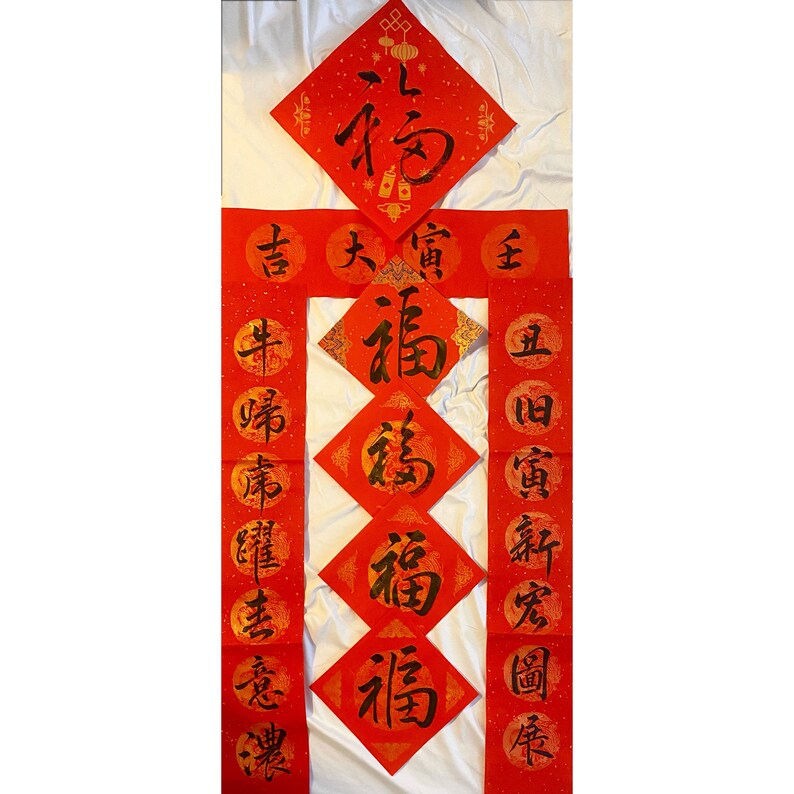 May include: Red and gold Chinese New Year decorations with the character "福" (Fu) meaning "good fortune" or "happiness" written in black calligraphy on each of the five diamond-shaped decorations and on the three vertical banners.