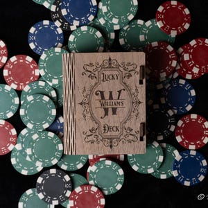 May include: A wooden box with a personalized inscription that reads "Lucky Williams Deck". The box is surrounded by red, blue, and green poker chips.