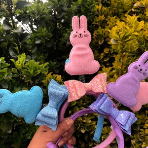 May include: A collection of Easter-themed headbands featuring felt bunny and bow designs in various pastel colors. The headbands include light blue, pink, purple, and glittery bows, perfect for spring celebrations.