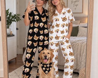 May include: Two-piece pajama sets featuring a repeating pattern of golden retriever and cat faces. One set is black with white and gold accents, while the other is white with black and gold accents. A golden retriever wears a matching black bandana.