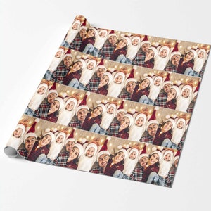 May include: A repeating pattern of a family wearing Santa hats and plaid shirts. The family is smiling and lying on a floor with string lights. The background is a light brown color.