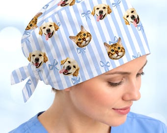 May include: A scrub cap featuring a light blue and white vertical striped pattern. The fabric is decorated with repeating images of golden retriever dog faces and cat faces, interspersed with small light blue bow illustrations.