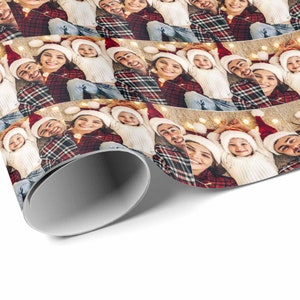 May include: A repeating pattern of a family wearing Santa hats, smiling and looking at the camera. The family is wearing red and white plaid shirts, white sweaters, and blue jeans. The background is a white surface with string lights.