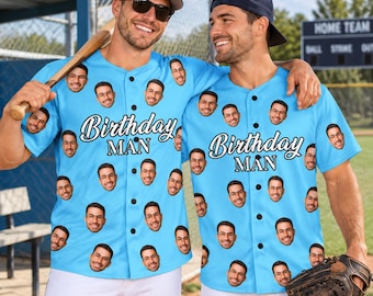 May include: Two light blue button-down baseball jerseys featuring a repeating pattern of a man's face with glasses and the text Birthday MAN printed in white with a black outline across the center of the chest on each garment.