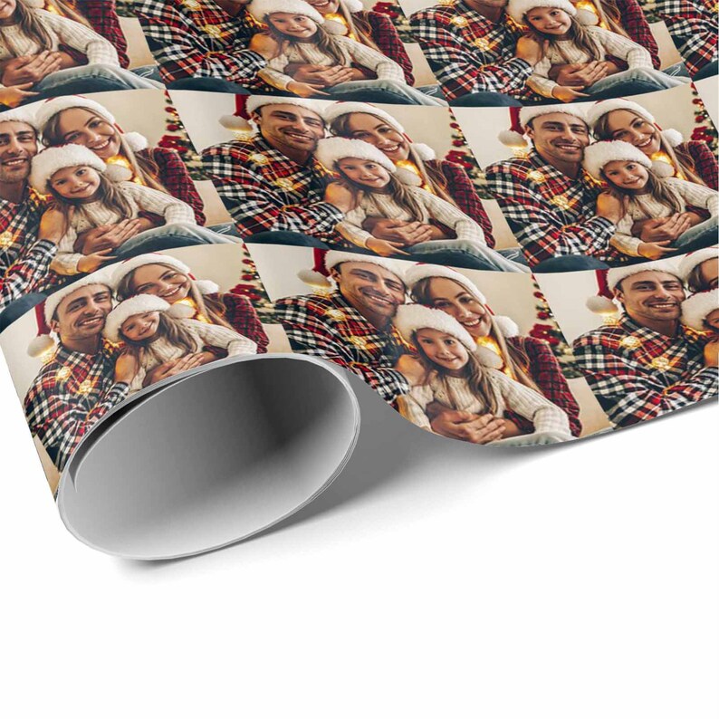 K&ouml;nnte beinhalten: Ein Weihnachtsgeschenkpapier mit einem Design, das eine dreik&ouml;pfige Familie zeigt, die Weihnachtsm&uuml;tzen tr&auml;gt und l&auml;chelt. Der Hintergrund ist ein rot-gr&uuml;nes Karomuster mit Weihnachtslichtern.