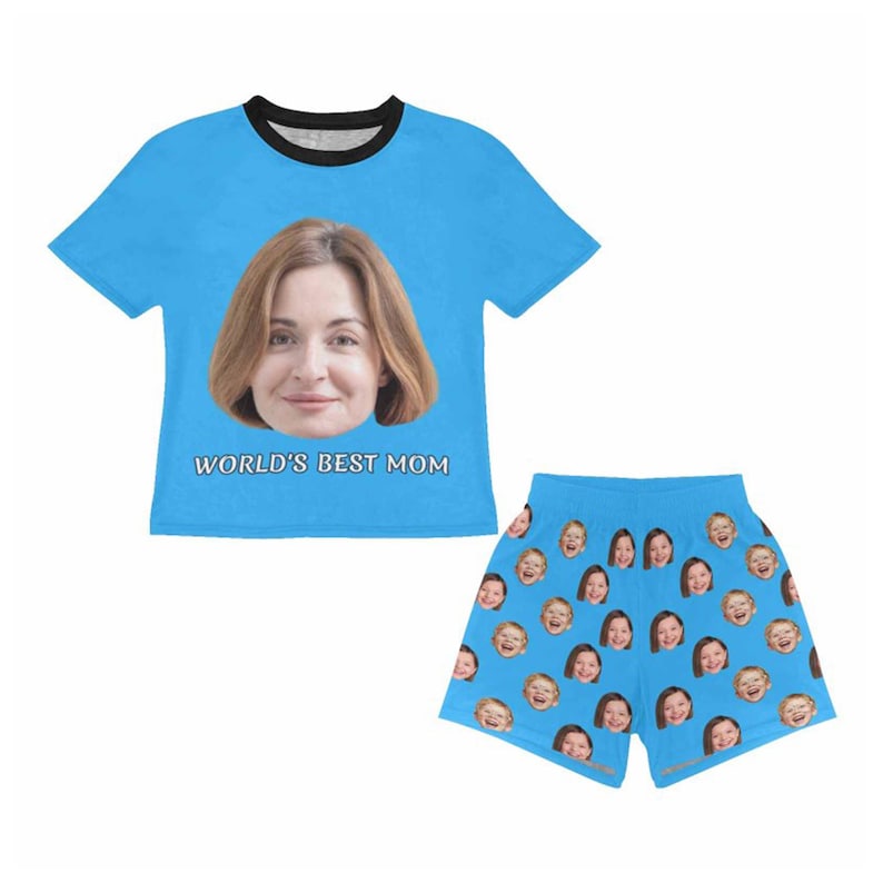 Pu&ograve; includere: Un pigiama blu chiaro composto da maglietta e pantaloncini. La maglietta presenta il volto di una donna e la scritta "WORLD'S BEST MOM". I pantaloncini sono ricoperti da immagini ripetute di volti.