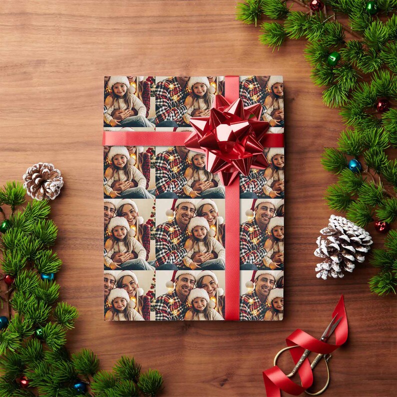 K&ouml;nnte beinhalten: Weihnachtsgeschenkpapier mit einem sich wiederholenden Muster einer dreik&ouml;pfigen Familie, einem Mann, einer Frau und einem M&auml;dchen, die Weihnachtsm&uuml;tzen tragen und l&auml;cheln. Das Papier ist mit rotem Band und einer roten Schleife verziert.