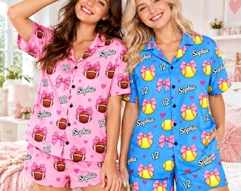 May include: Two sets of short-sleeved button-down pajamas with shorts. The pink set features footballs, pink bows, hearts, the number 12, and the name Sophia. The blue set features yellow softballs, pink bows, hearts, the number 12, and the name Sophia.