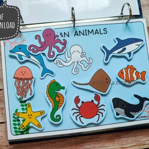 May include: A blue binder with a light blue background and colorful illustrations of ocean animals. The animals include a dolphin, octopus, jellyfish, starfish, seahorse, crab, stingray, whale, and clownfish. The text "Ocean Animals" is printed on the binder.
