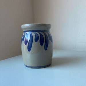 May include: A grey ceramic vase with a blue and white design. The vase has a rounded body and a wide mouth.