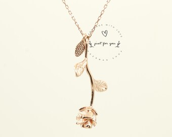 May include: Gold rose necklace with a delicate stem and leaves. The pendant features a small rose with intricate details. The necklace is on a white background with the text "Made with love, just for you."