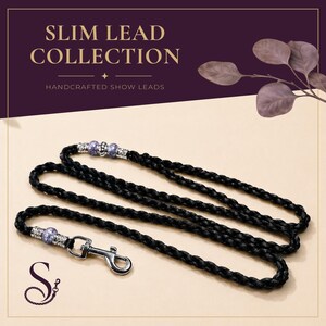 May include: A black braided show lead featuring a silver-toned metal swivel snap hook and decorative accents with light purple beads and silver-toned spacers. The text SLIM LEAD COLLECTION HANDCRAFTED SHOW LEADS is visible at the top of the image.