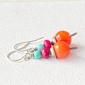 May include: A pair of dangle earrings with orange, pink, and turquoise gemstone beads and silver accents.