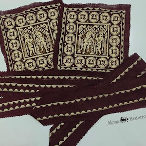May include: Two square burgundy fabric patches with a cream-colored illustration of figures and architectural elements. Below are burgundy fabric strips with a cream-colored scalloped edge. The patches and strips have a textured appearance.