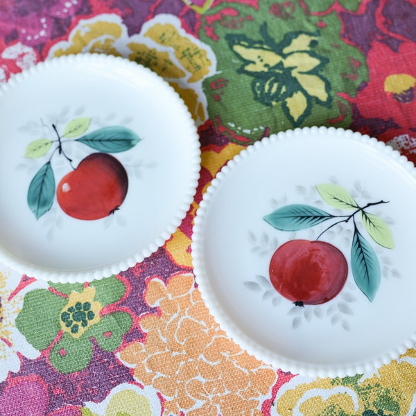 May include: Two white ceramic plates with a beaded edge. Each plate features a hand-painted design of a red apple with green leaves on a white background.