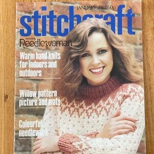 May include: A magazine cover featuring a woman wearing a pink and white knitted jumper. The magazine is titled "Stitchcraft" and includes the words "Needlewoman", "Warm hand knits for indoors and outdoors", "Willow pattern picture and mats", and "Colourful needlework".