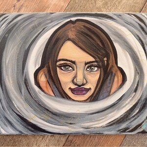 Peut inclure: Une peinture d'un visage de femme avec des cheveux bruns et des yeux bleus. La femme regarde directement le spectateur. L'arrière-plan est un motif tourbillonnant de gris et de blanc.