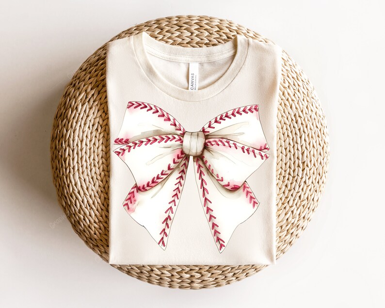 May include: A beige t-shirt with a white and red baseball-stitched bow design.