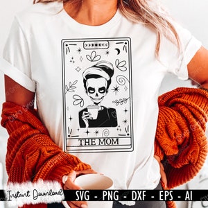 May include: A black and white illustration of a tarot card with a skull holding a coffee cup. The card is labelled "The Mom".