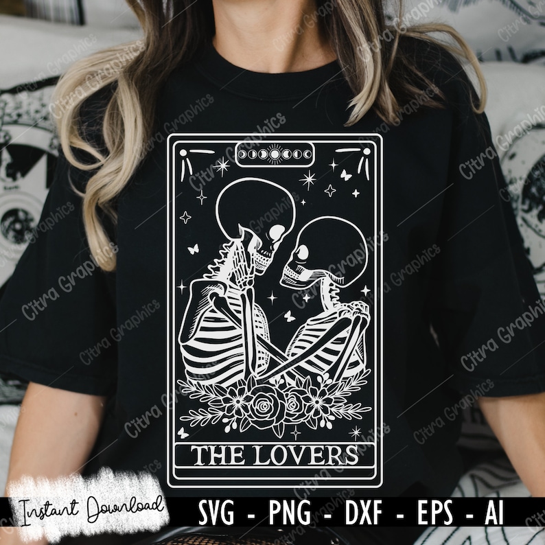 May include: A black and white tarot card illustration of The Lovers card. The card features two skeletons embracing with flowers at their feet. The card is framed with a black border and has the text "THE LOVERS" at the bottom.