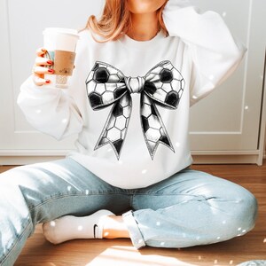 Op de afbeelding: Wit sweatshirt met een groot zwart-wit voetbalstrikontwerp. De strik is gedetailleerd met zeshoekige patronen en een lintachtige vorm. Een casual, alledaags kledingstuk.