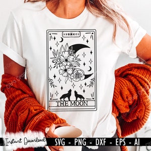 May include: A black and white graphic design of a tarot card with the words "THE MOON" at the bottom. The card features a crescent moon, two howling wolves, and a floral design.