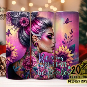May include: A pink and purple tumbler with a woman's face and flowers. The text on the tumbler reads "Be strong, be brave, be fearless".