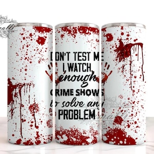 May include: White stainless steel tumbler with a red blood splatter design. The tumbler has black text that reads "Don't test me, I watch enough crime shows to solve any problem."