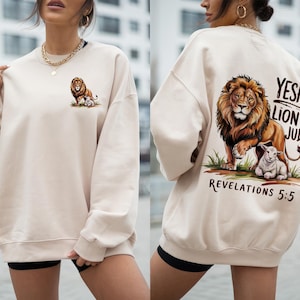 Puede incluir: Una sudadera de color crema con un gráfico de león y cordero en la espalda. El gráfico incluye el texto "Yeshua Lion of Judah Revelations 5:5".