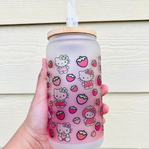 Puede incluir: Una botella de agua de vidrio esmerilado con tapa de bamb&uacute; y dise&ntilde;o de Hello Kitty y fresas. La botella tiene una pajita.