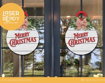 May include: Two round Christmas decorations with the text "MERRY CHRISTMAS" in red. Each has a white wooden background with horizontal lines, a red loop, a pink bow, and green leaves. The decorations are hanging on a glass door.