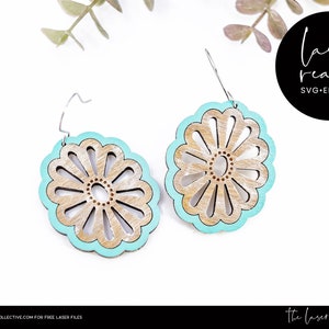 May include: A pair of laser cut wooden earrings with a turquoise blue border and a floral design. The earrings are ready to be assembled and are available in SVG, EPS, and DXF formats.