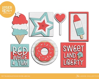 Puede incluir: Señales de madera de temática roja, blanca y azul con varios diseños que incluyen una estrella, un cono de helado, una dona, una paleta de hielo y un corazón. Las señales presentan el texto "Red White & Yum" y "Sweet Land of Liberty".