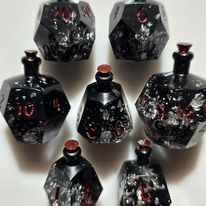 May include: Set of seven black polyhedral dice with red numbering and silver glitter inclusions. Each die is shaped like a potion bottle with a red stopper. Ideal for tabletop gaming.