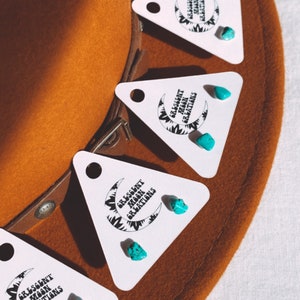 May include: Turquoise gemstone earrings on white triangle cards with the text "Crescent Moon Creations".
